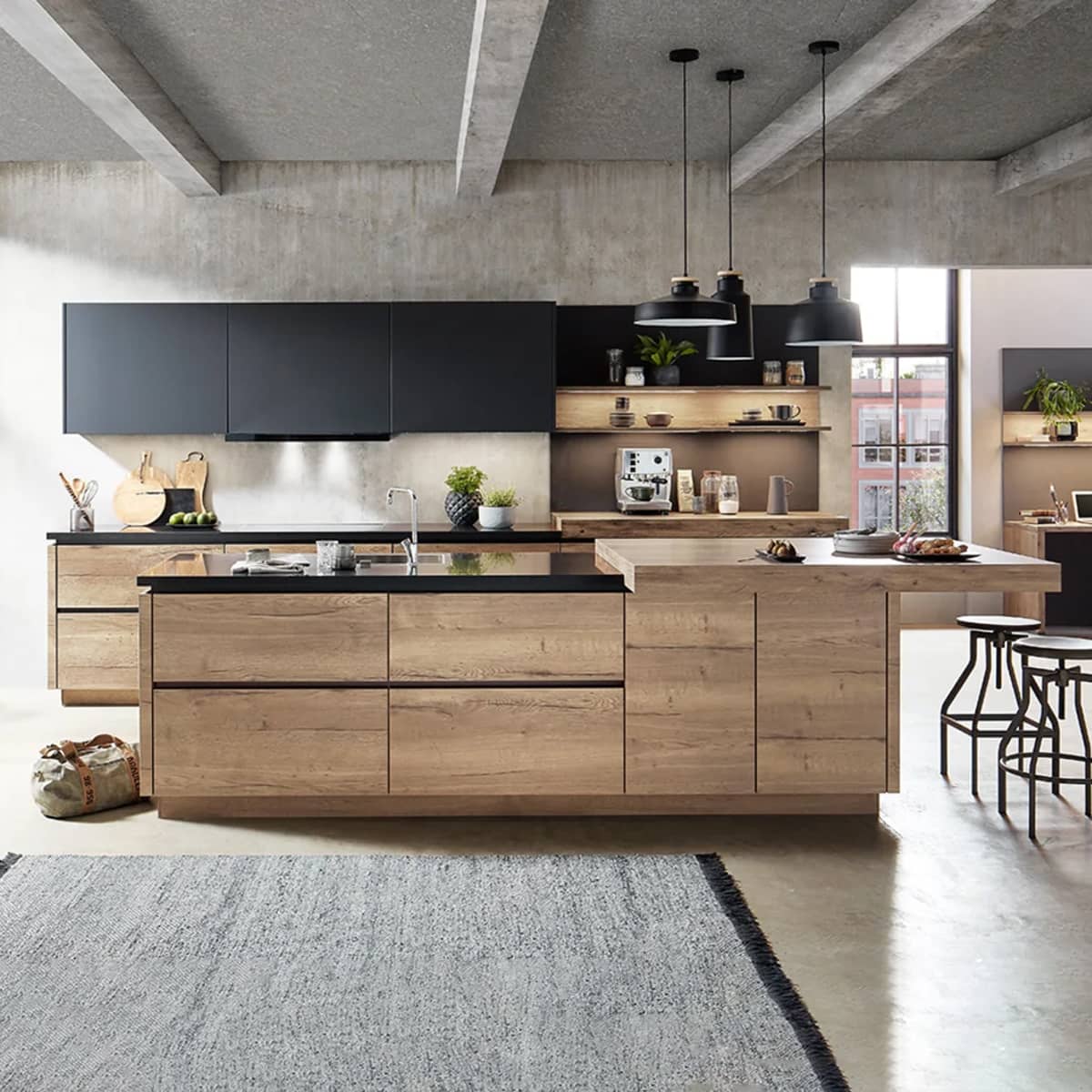 Modern industrial nobilia Structura kitchen featuring natural oak wood cabinets, black accent wall units, and a large kitchen island against a raw concrete ceiling.