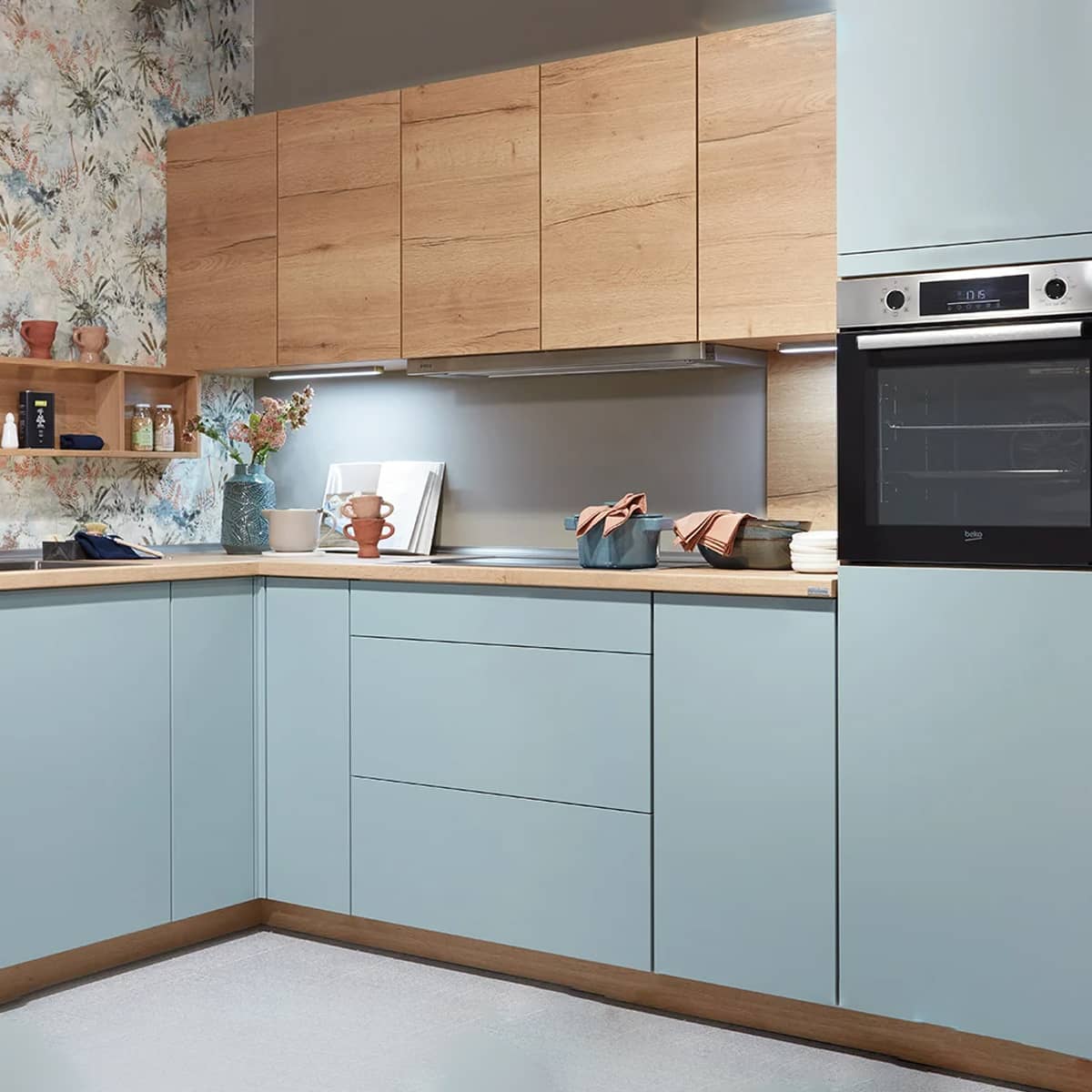 Touch Kitchen 337 Ergonomic aqua supermatt kitchen featuring TOUCH 337 fronts, light oak upper cabinets, and a decorative floral niche cladding.