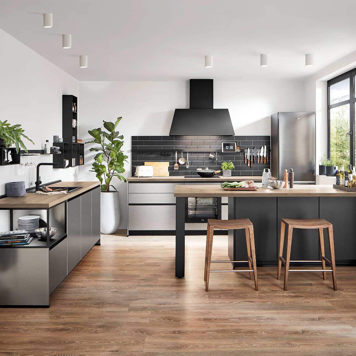 Modern Nobilia Inox 216 kitchen with brushed stainless steel cabinets, black backsplash, and wooden flooring.