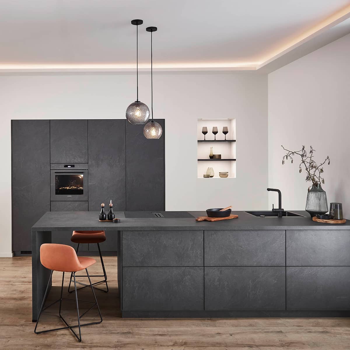 A spacious Nobilia StoneArt kitchen featuring sleek dark stone‑effect cabinets, a large kitchen island, integrated appliances, pendant lighting, and minimalist shelving for a modern, premium interior.