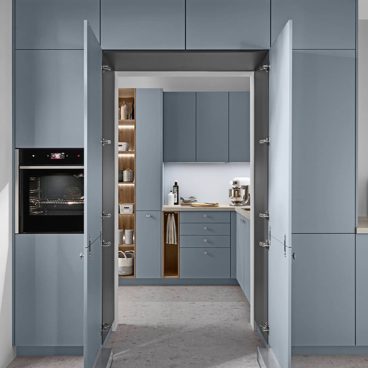 Senso Kitchen 485 - Blue Kitchen with concealed pantry Contemporary blue kitchen cabinets featuring a double-door concealed walk-in pantry and integrated oven with internal LED lighting.