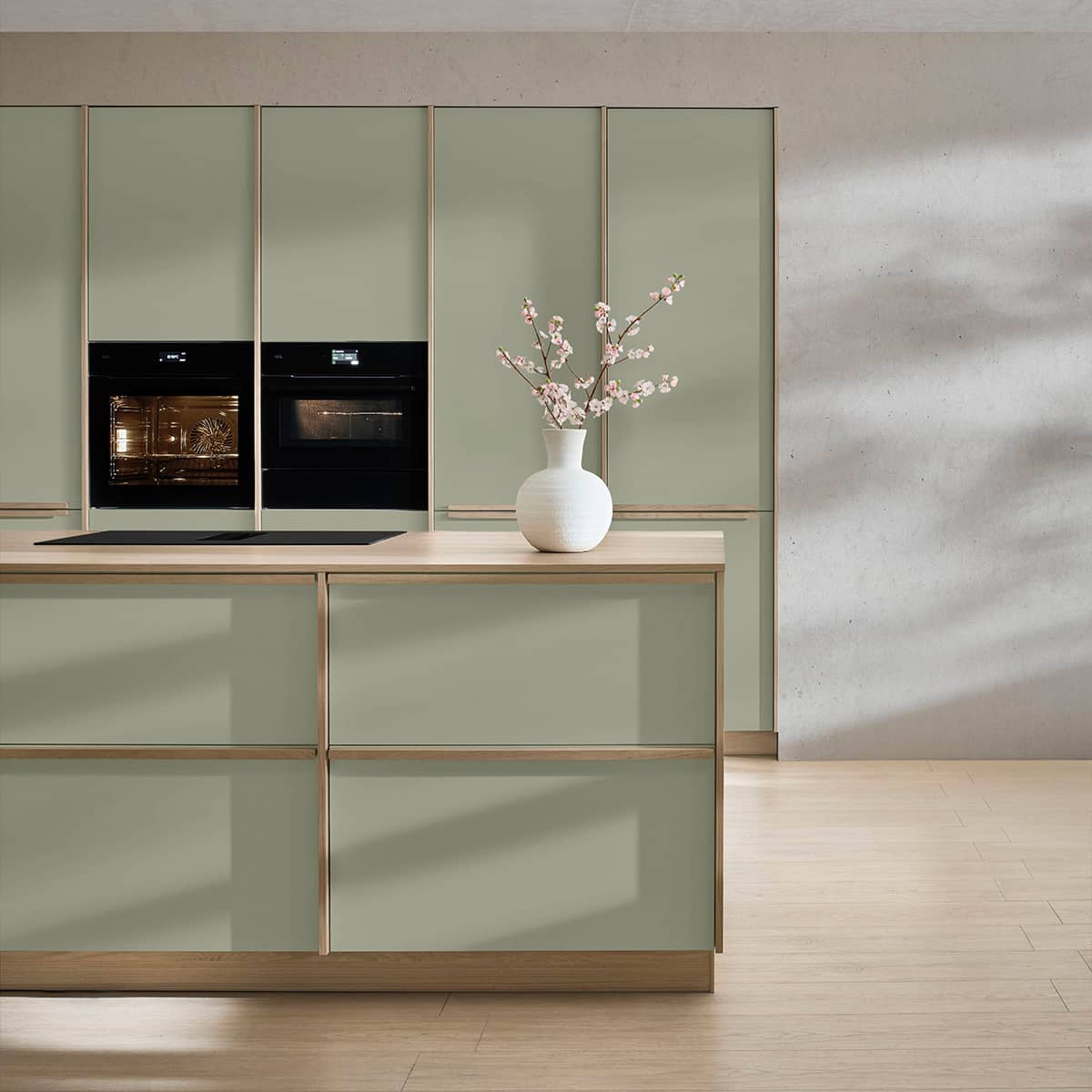 Senso Kitchen 488 - Framed Door Kitchen in Green Sage green modern kitchen featuring slim framed cabinet doors, light wood accents, and integrated black kitchen appliances.