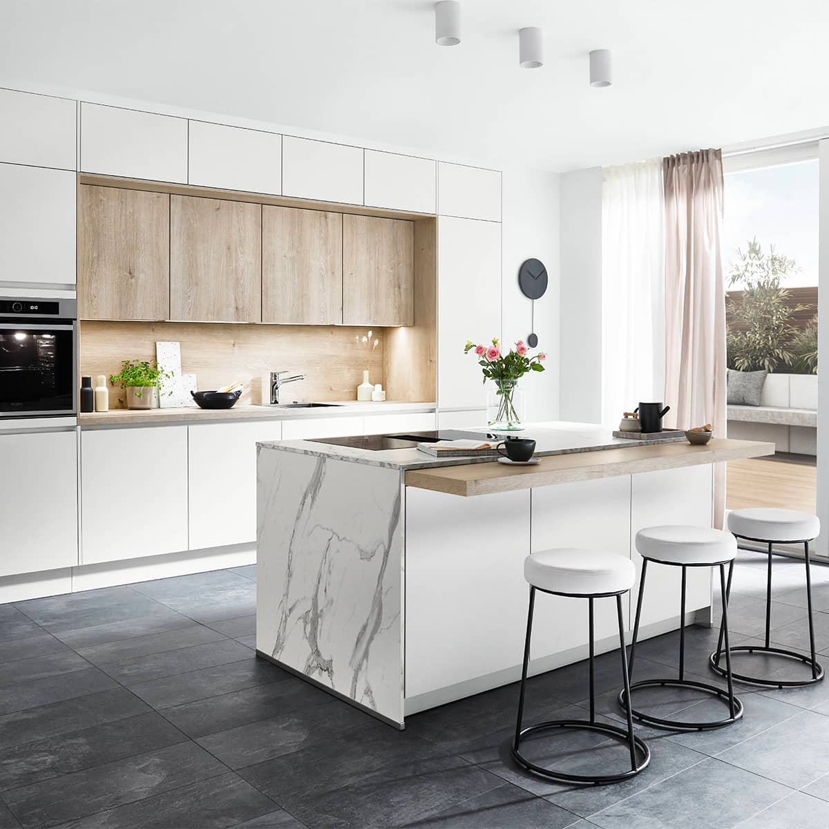Senso Kitchen 488 Modern white handleless kitchen featuring a marble-effect waterfall island with a light wood breakfast bar and matching wooden backsplash.