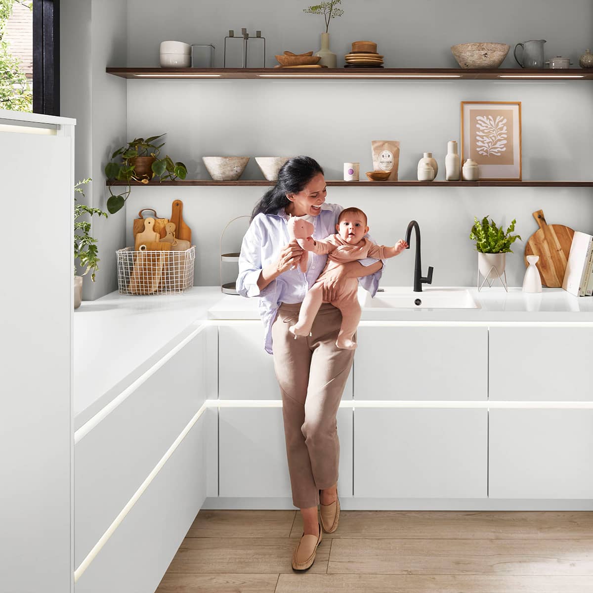Senso Kitchen 490 - White kitchen with mother and baby Bright white modern kitchen with integrated LED strip lighting under the countertops and minimalist open shelving.
