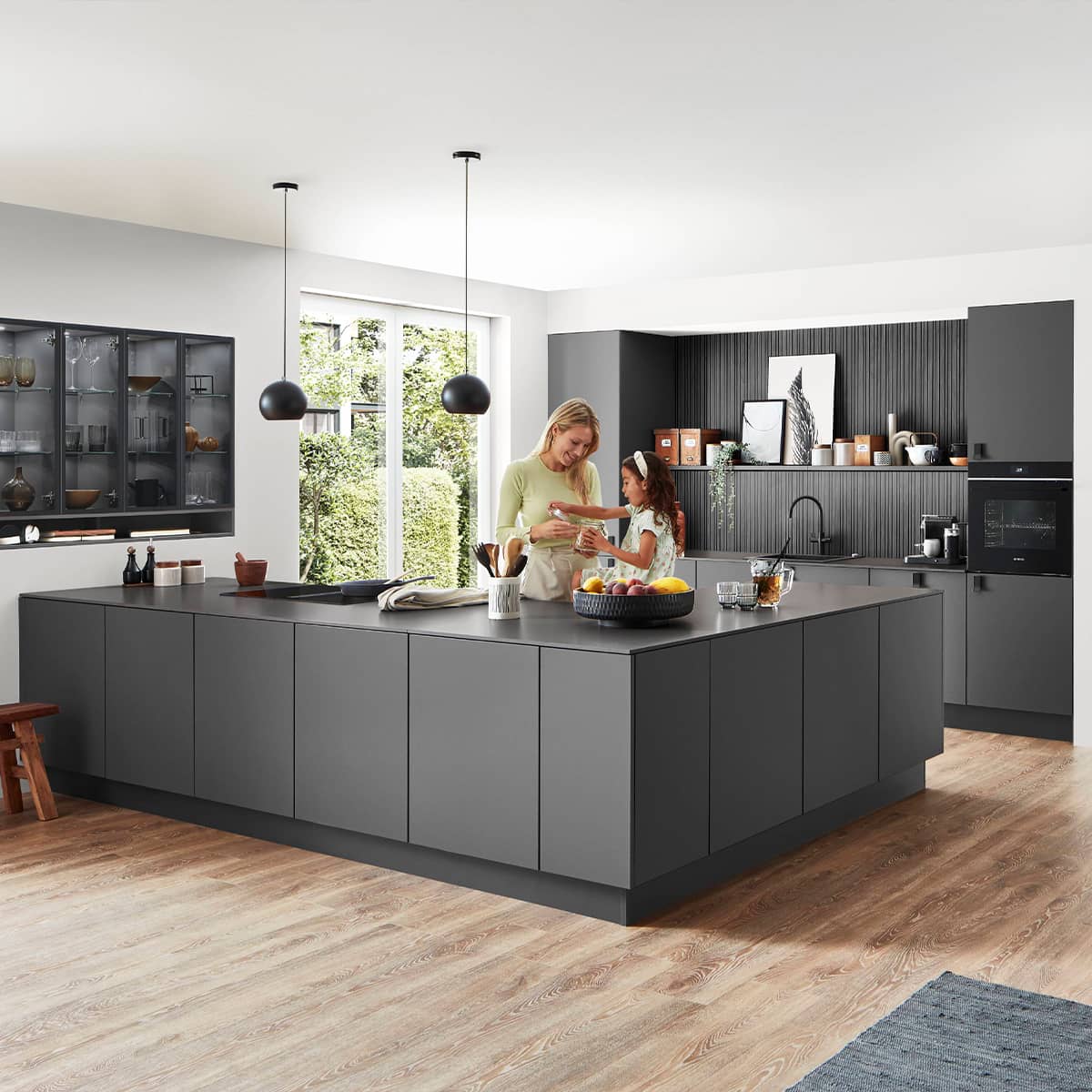 Senso Kitchen 491 - modern minimalist kitchen with human element Large charcoal grey matte kitchen island in a minimalist open-plan home with industrial pendant lighting and glass-fronted cabinets.
