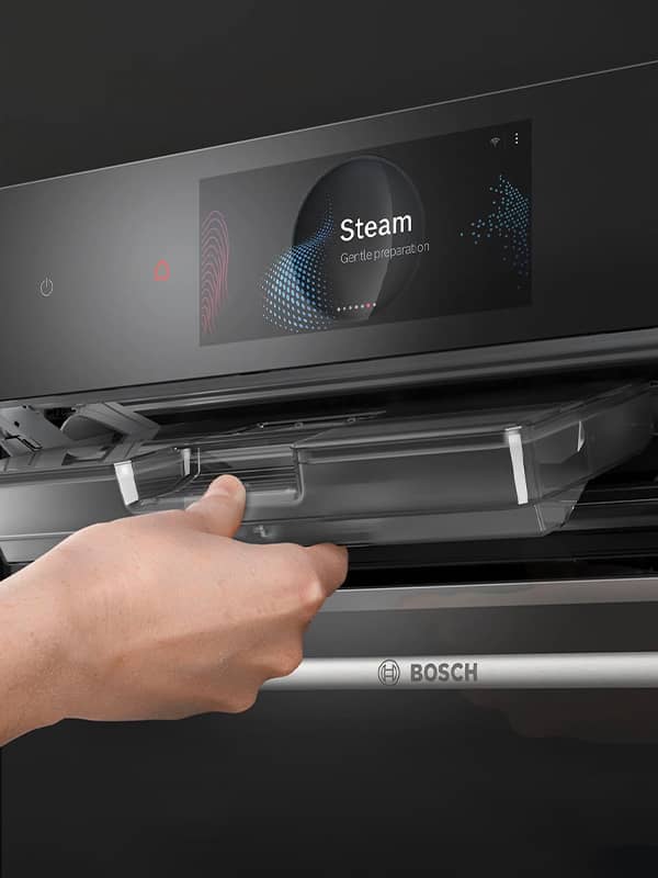 Bosch Series 8 oven with steam function on display, a hand opening the steam compartment for adding water