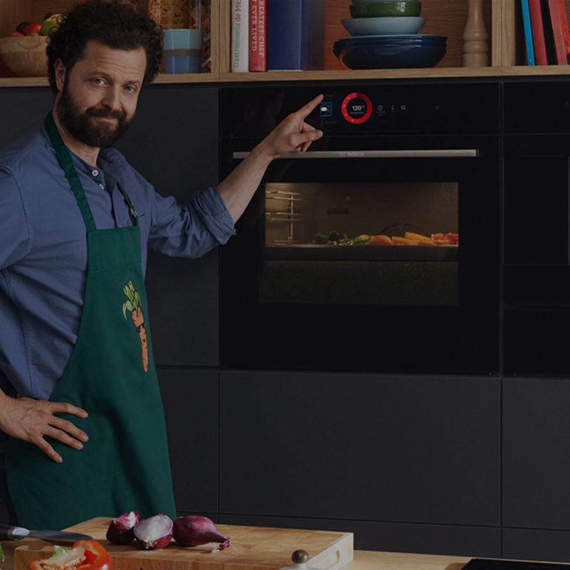 Man interacting with the Bosch Series 8 oven on a mobile-optimized, darker banner, highlighting the touch control panel.