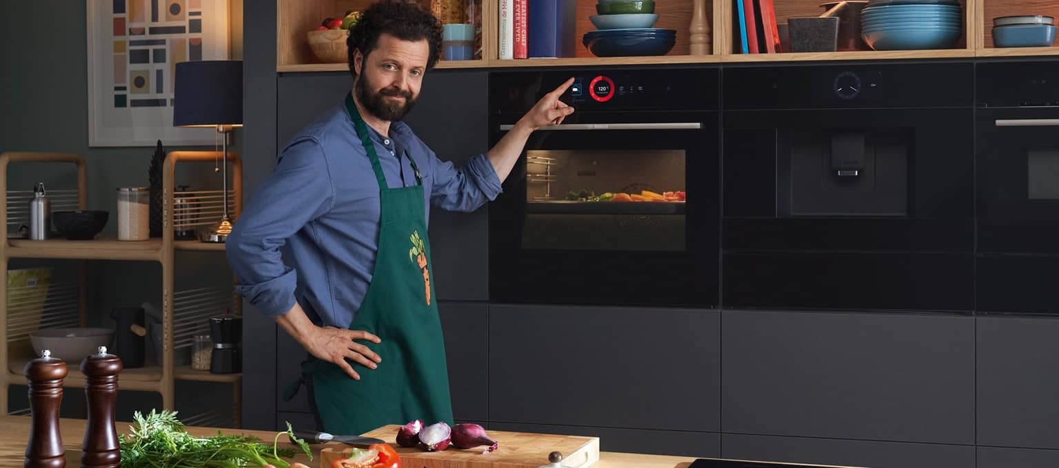 Man holding his finger to the Bosch Series 8 oven, interacting with the sleek touch control panel.