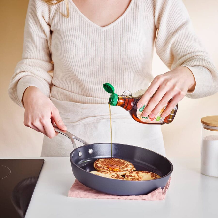 Cooking pan cakes in frypan whilst pouring maple syrup