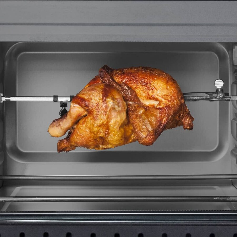Close-up of CASO TO 20 oven cavity with golden-brown rotisserie chicken inside, shown on spit rod.
