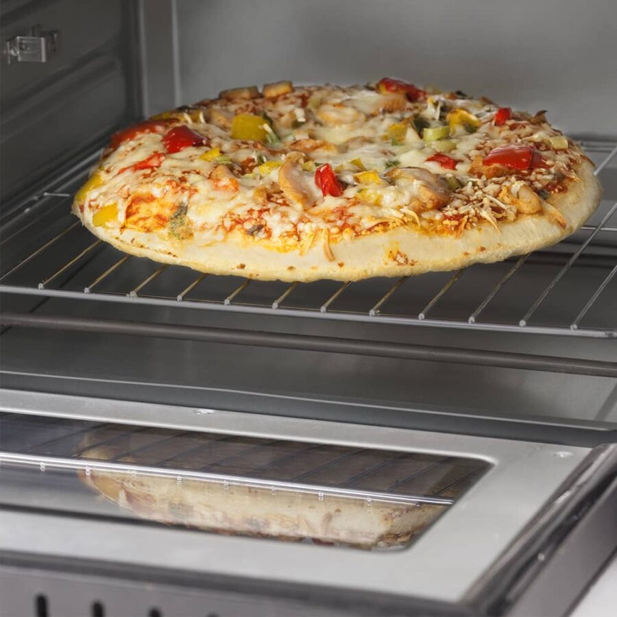 Close-up of CASO TO 20 Electronic Oven with pizza baking on wire rack inside oven cavity.