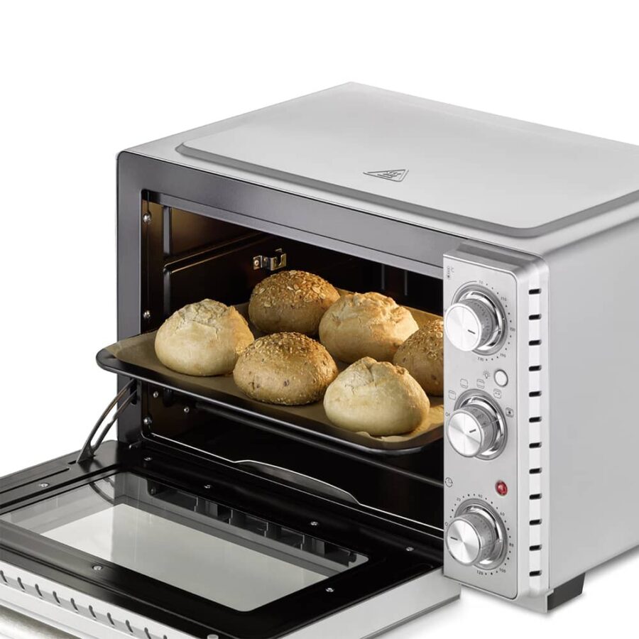CASO TO 26 Silver Oven with open door and light on, baking tray inside holding six cooked buns on a baking sheet.