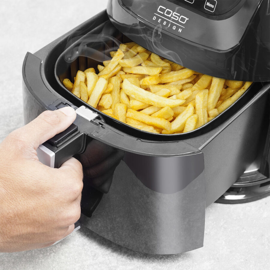 Hand pulling out Caso Air Fry AF 255 drawer with cooked fries inside, steam rising, on white background.